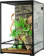 Glass reptile terrarium with green snake, natural branches, and artificial plants inside enclosure