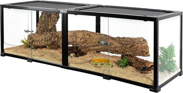 Large glass reptile terrarium with sliding doors, logs, artificial plants, and sand substrate