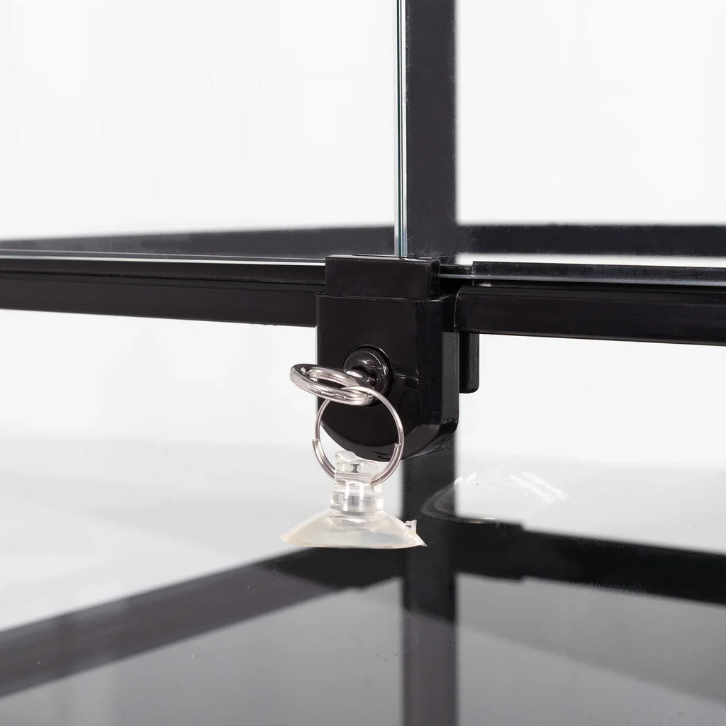 Close-up of a reptile terrarium glass corner with a locking latch and suction cup ring.