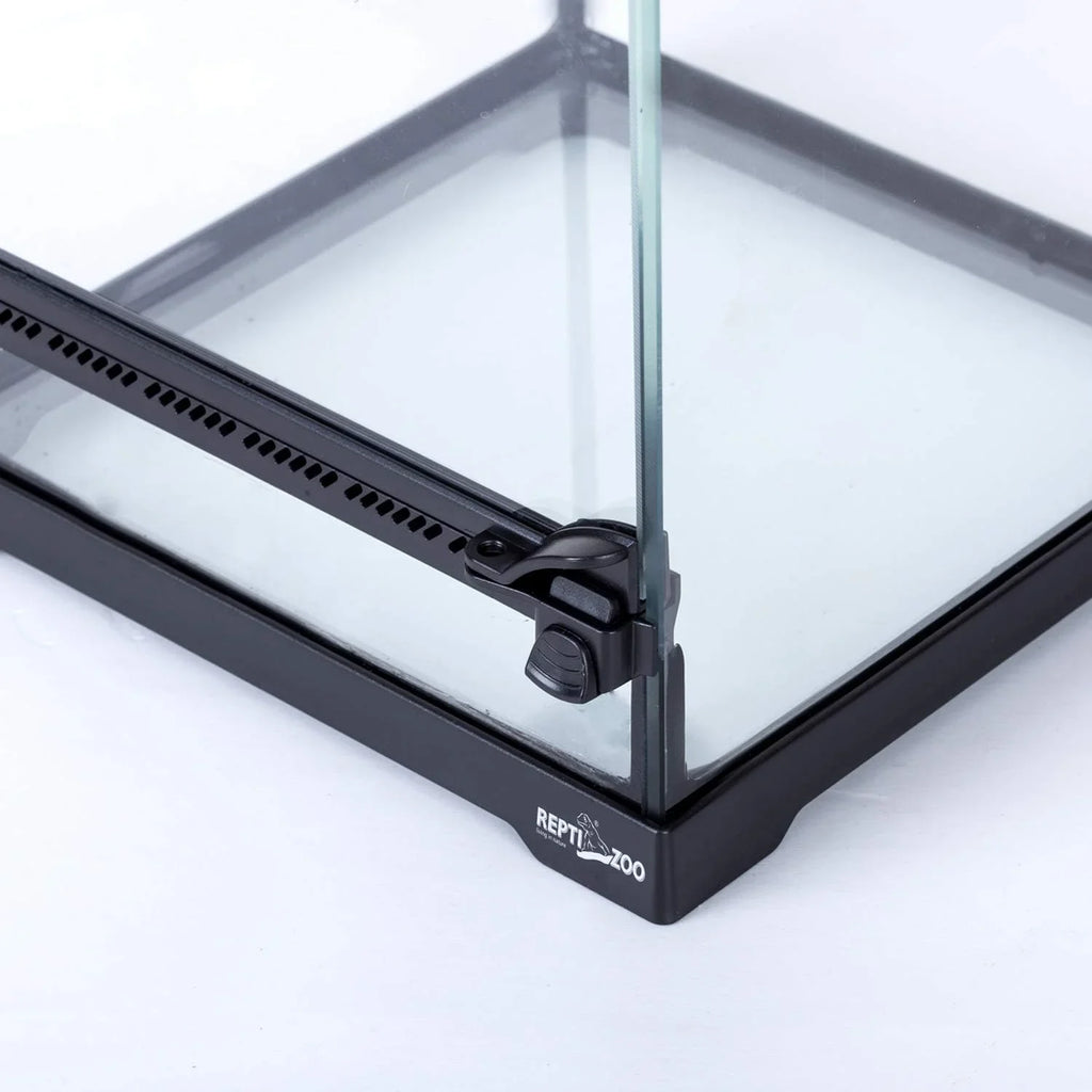 Close-up of glass reptile terrarium corner with secure lock and ventilation strip