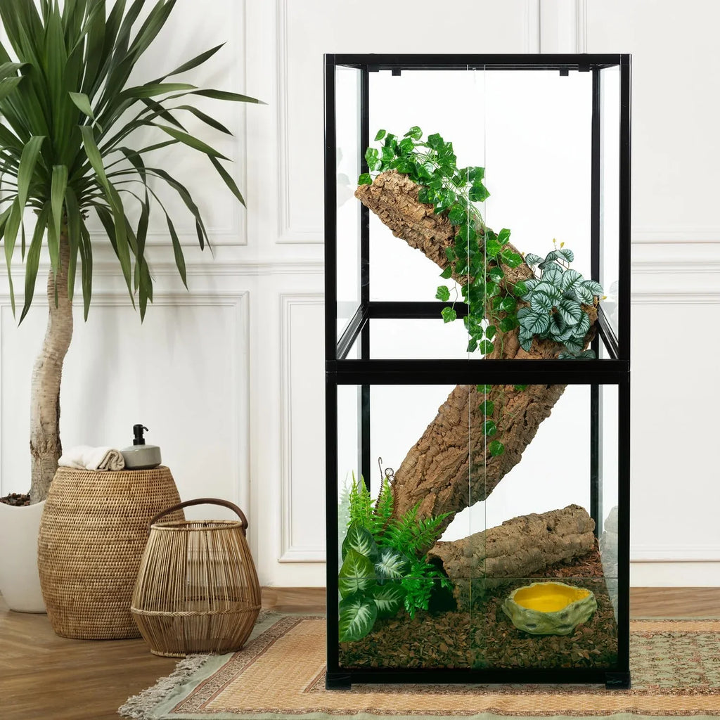Glass reptile terrarium with climbing log, artificial plants, and water dish in a modern room
