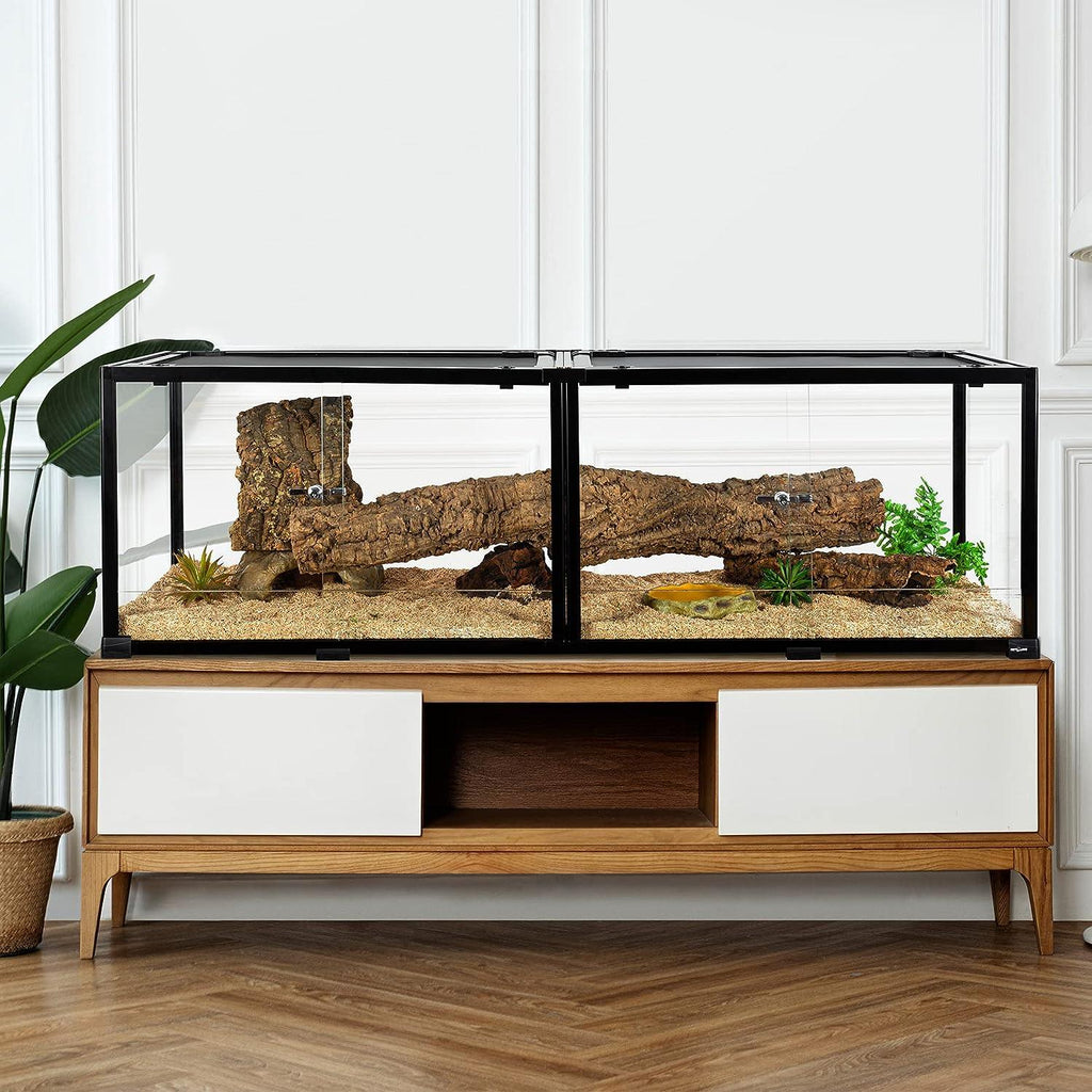 Modern reptile terrarium with sand, wood log, and plants on wooden cabinet