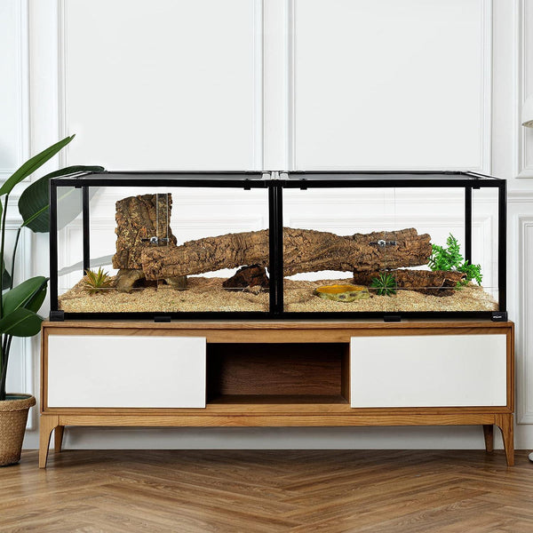 Modern reptile terrarium with sand, wood log, and plants on wooden cabinet