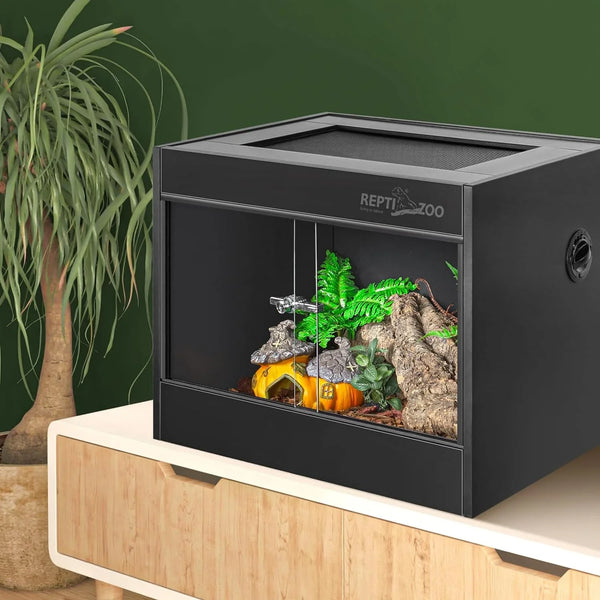 Glass reptile terrarium with sliding doors, log décor, and artificial plants on wooden cabinet