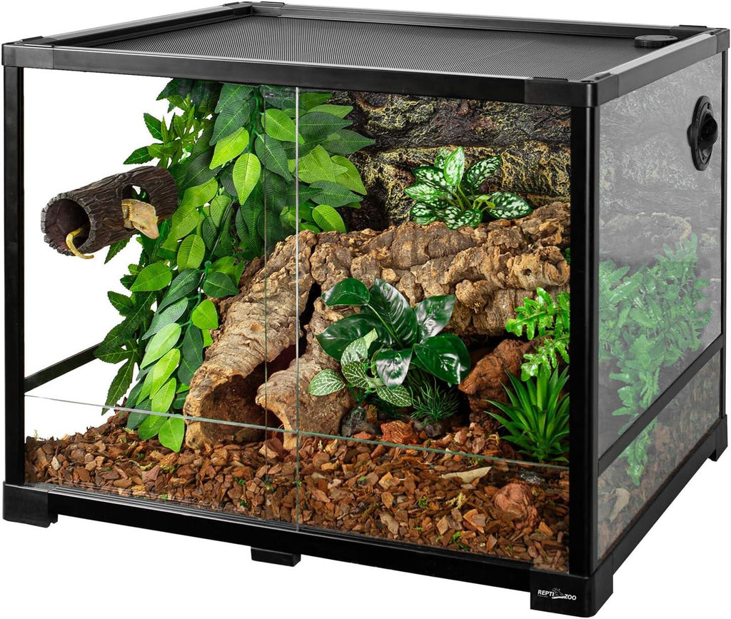 Glass reptile terrarium with screen top, faux plants, logs, and natural substrate
