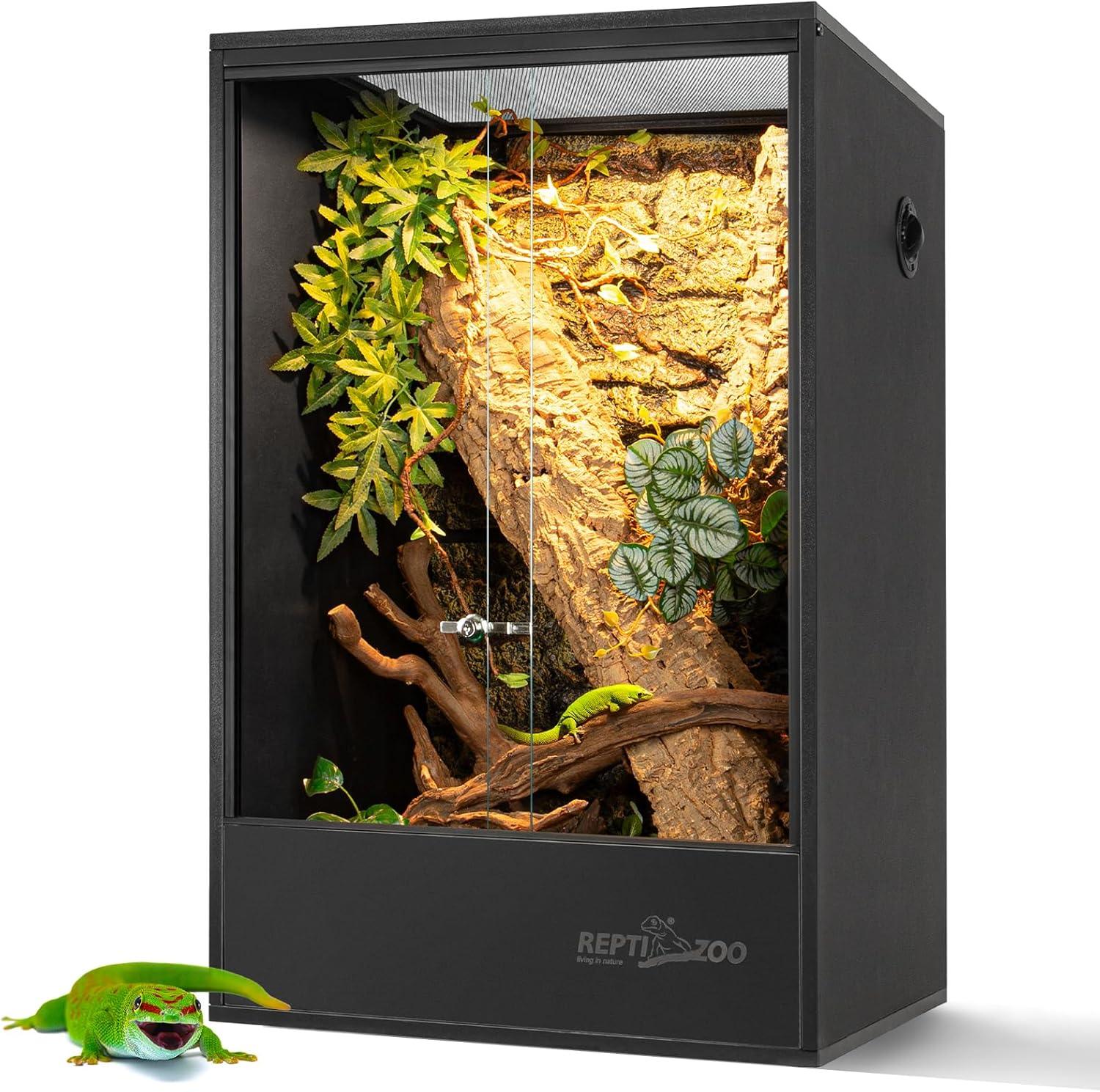Glass reptile terrarium with front doors, branch, foliage, and a green lizard inside
