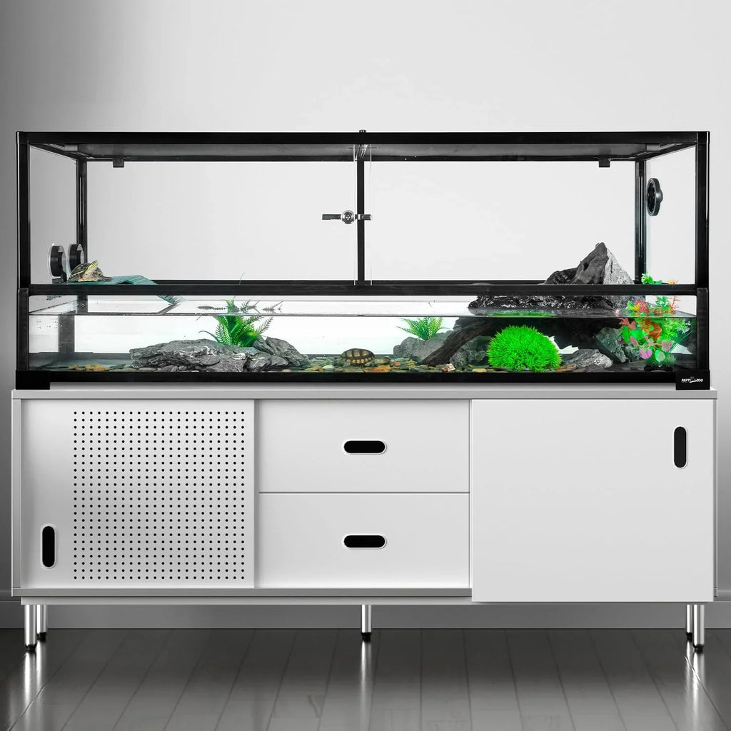 Large glass reptile terrarium with rocks, plants, and water on modern white stand.
