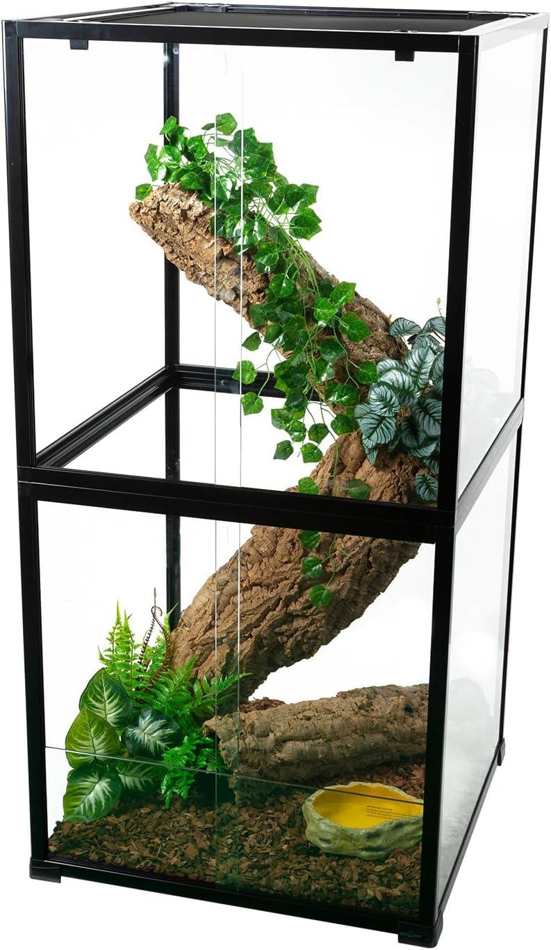 Glass reptile terrarium with climbing branch, artificial plants, and a water dish inside.