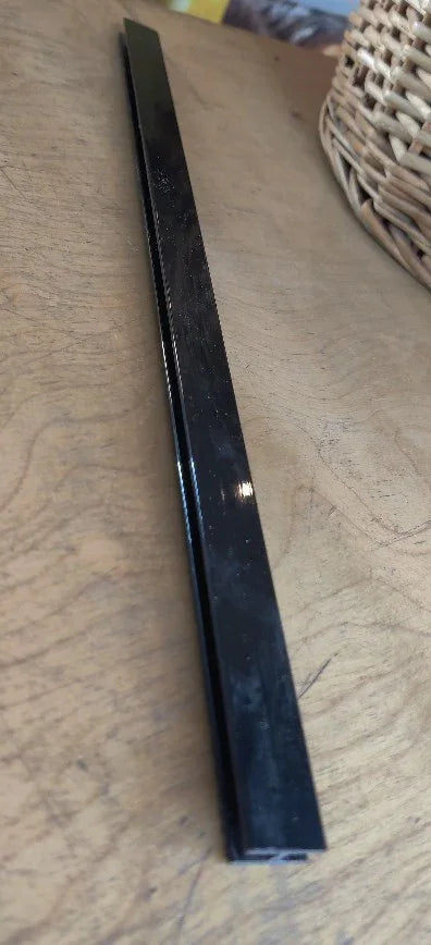 Long black plastic frame strip for reptile terrarium cage on wooden surface