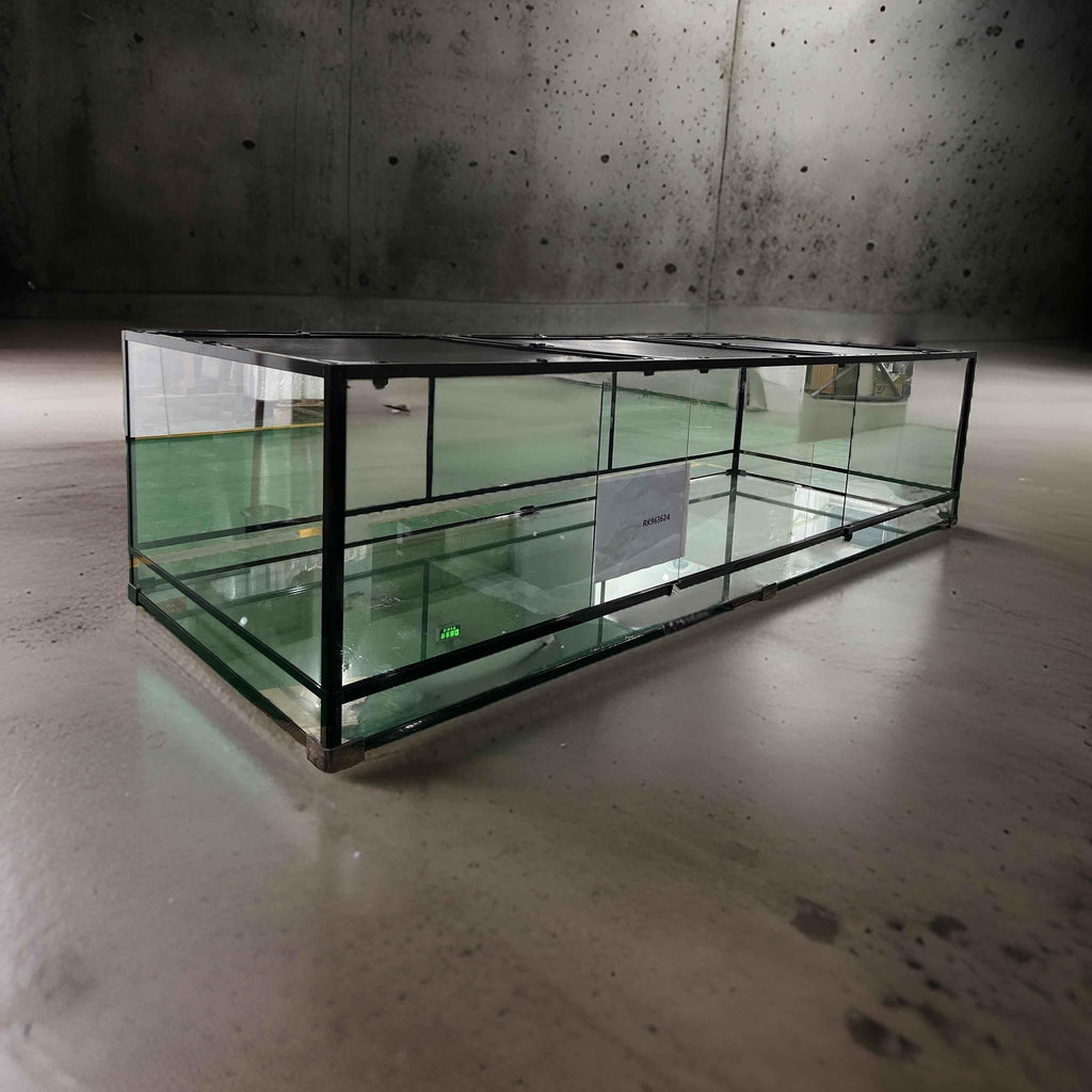 Large glass reptile terrarium cage with sliding doors on concrete floor