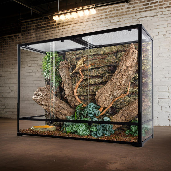 Large glass reptile terrarium with mesh top, natural wood branches, and artificial plants