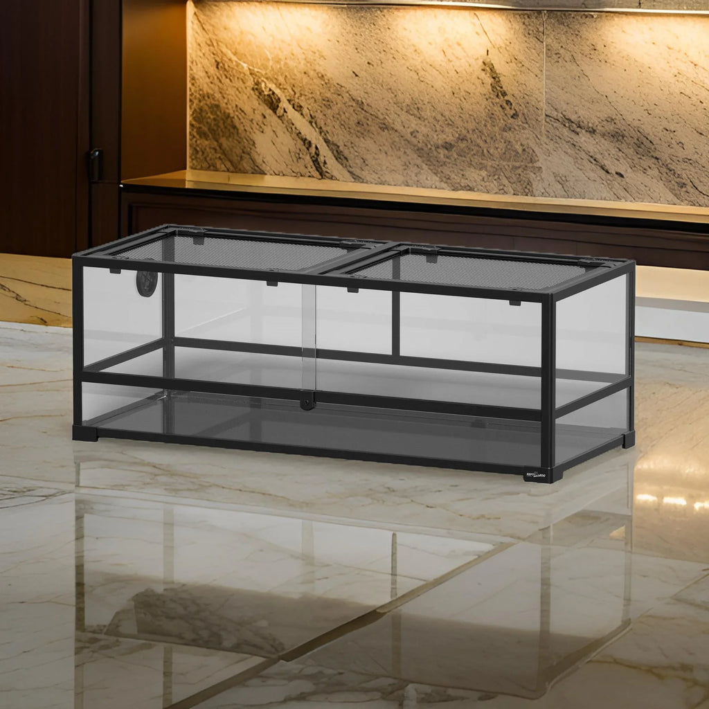 Large glass reptile terrarium with metal frame and mesh top on marble floor
