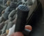 Close-up of a black terrarium misting nozzle with rocks and glass in the background
